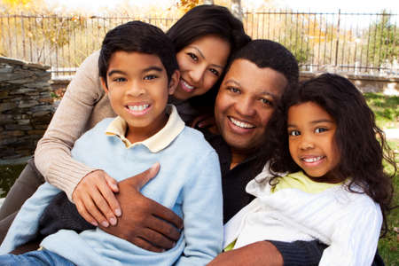 Biracial family laughing and smiling outside.の写真素材