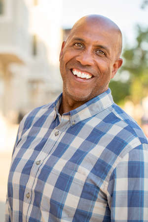 Happy mature African American man smiling outside.
