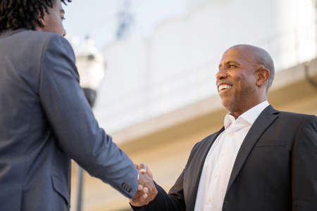 Mature African American casually dressed businessman shaking hands.