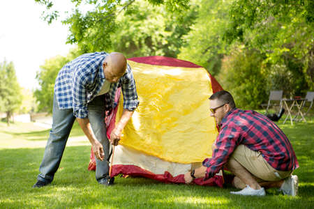Friends hanging out camping and setting up a tent.の写真素材