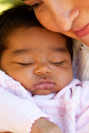 Hispanic mom kissing and hugging her baby.の写真素材