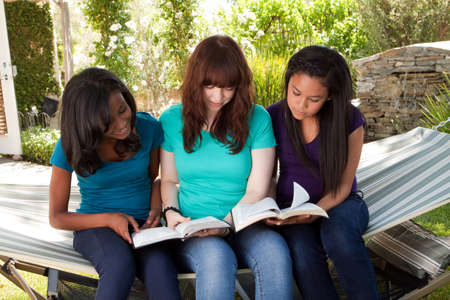 Diverse group of teenage girls reading outside.