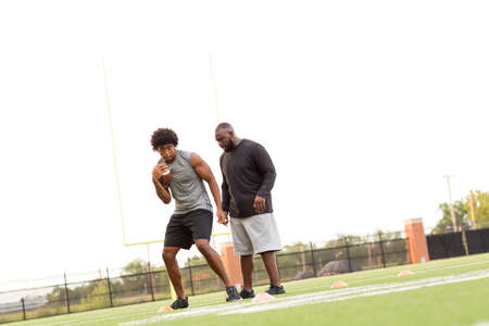 American Football coach training a young athlete.の写真素材