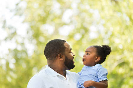 African American father hugging and holding his little girl.の写真素材