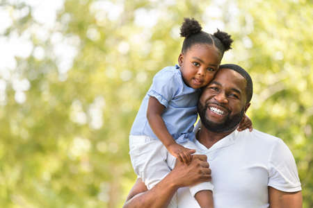 African American father hugging and holding his little girl.の写真素材