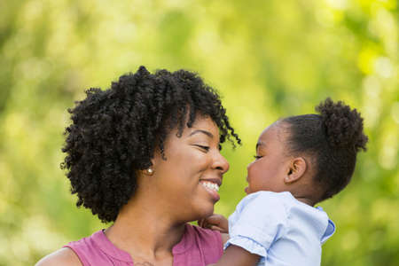 African American mother laughing and hugging her daughter.の写真素材