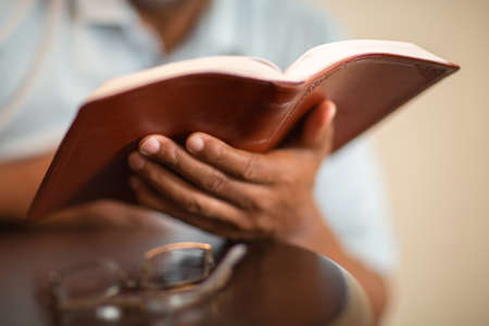 African American man praying and reading the Bible.