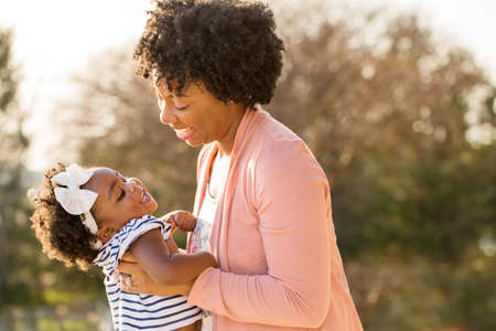 African American mother laughing and holding her daughter.