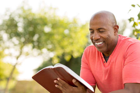 African American man praying and reading the Bible.