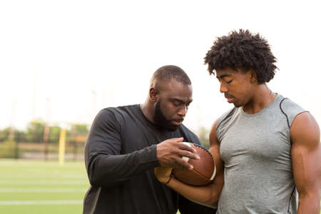 American Football coach training a young athlete.の写真素材