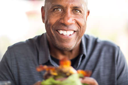 African American man eating a burger without a bun.の写真素材