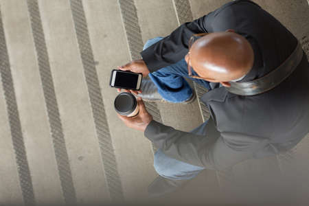 African American businessman drinking coffee and texting.