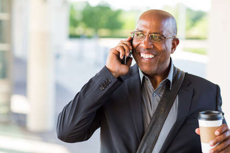 African American businessman drinking coffee and texting.の写真素材