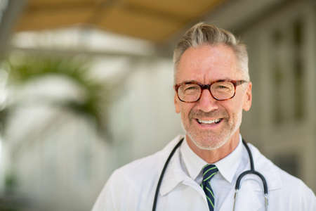 Portrait of a mature handsome doctor at a medical office.の写真素材