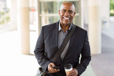 African American businessman drinking coffee and texting.