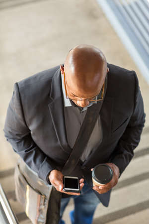 African American businessman drinking coffee and texting.
