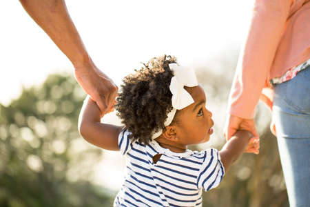 Little girl holding hands with her parents.の写真素材