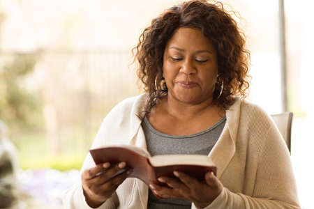 Mature African American woman sitting outside reading.
