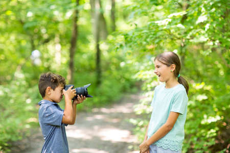 Young boy taking photo of his sister in the forest.の写真素材