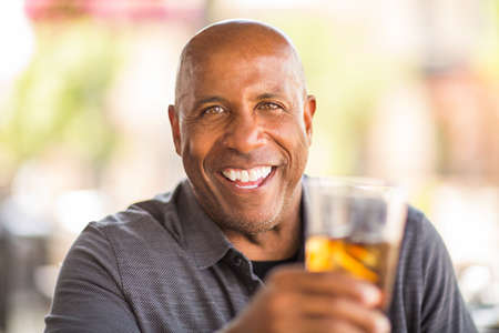 Mature African American man drinking at a restaurant.の写真素材