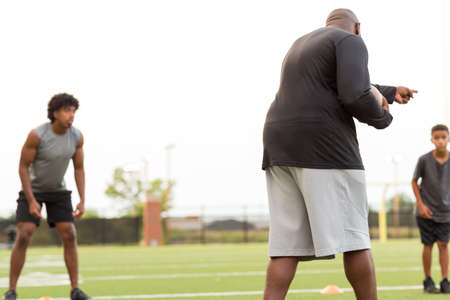 American Football coach training a young athlete.の写真素材
