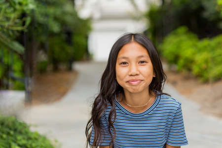 Portrait of a young Asian girl smiling outside.