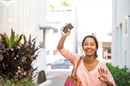 Young woman waving her hand for her ride.