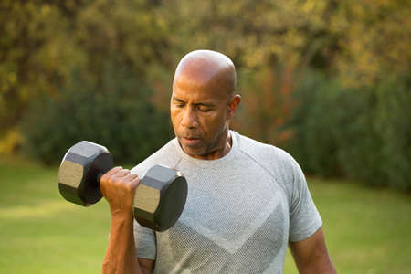 Fit African American man lifting weights outside.の写真素材