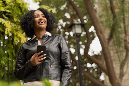Confident African American Woman walking and texting.の写真素材