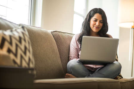 Young woman working at home sitting on a sofa.の写真素材
