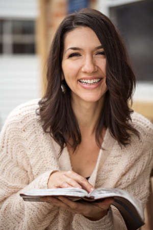 Happy young hispanic woman sitting outside reading.の写真素材