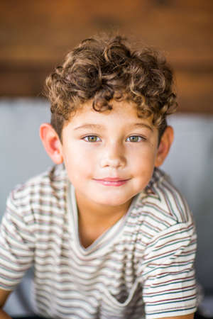 Handsome young boy with curly hair smiling.の写真素材