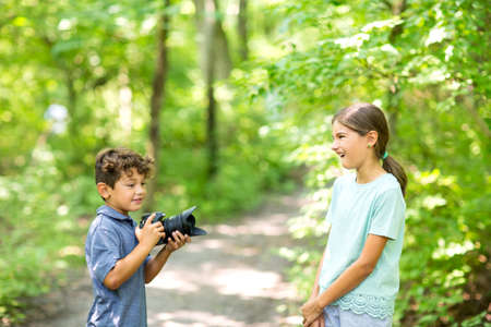 Young boy taking photo of his sister in the forest.の写真素材