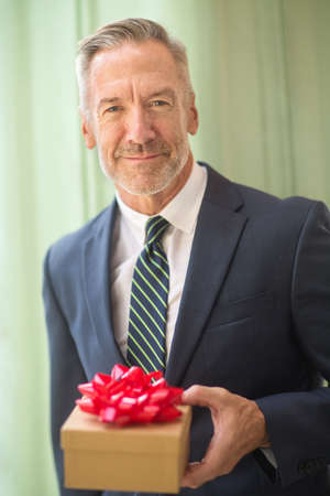 Mature handsome man giving a gift stock photo