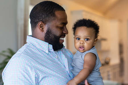 Loving father smiling and playing with his son at home.の写真素材