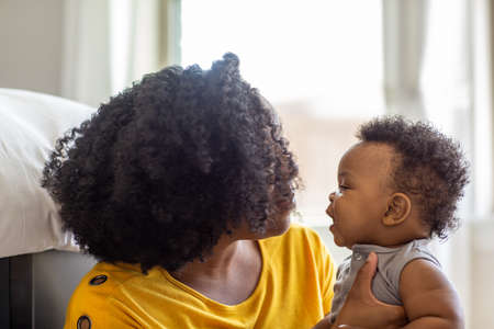 Happy mother smiling and playing with her son at home.の写真素材