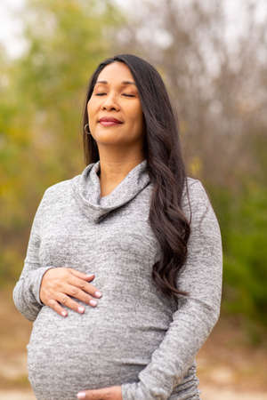 Happy Asian pregnant woman holding her stomachの写真素材