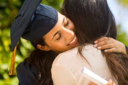 Mother hugging her daugher at her graduationの写真素材