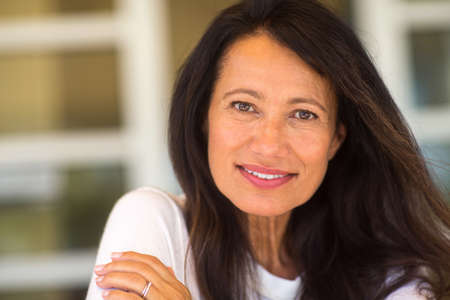 Portrait of a beautiful mature woman sitting on the sofaの写真素材