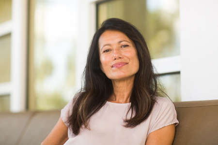 Portrait of a beautiful mature woman sitting on the sofaの写真素材