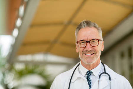 Portrait of a mature handsome doctor at a medical office.の写真素材