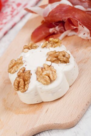 Tasty cheese with walnuts on chopping boardの写真素材