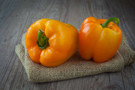 Fresh orange peppers on a wooden backgroundの写真素材