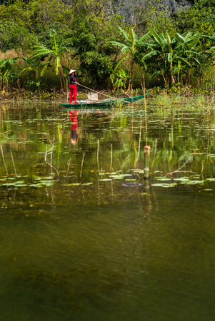 Vietnamese woman paddling on the river in the province of Ninh Binh, Vietnamの写真素材