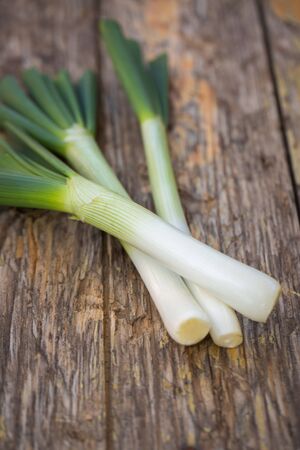 Fresh raw spring onions on a wooden boardの写真素材