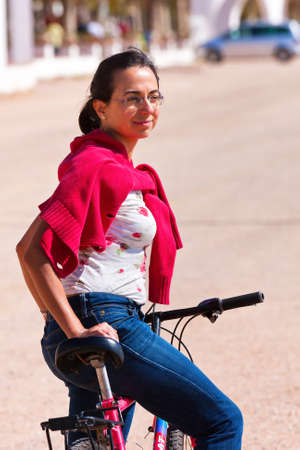 Happy young girl poses in front of the camera with a bike