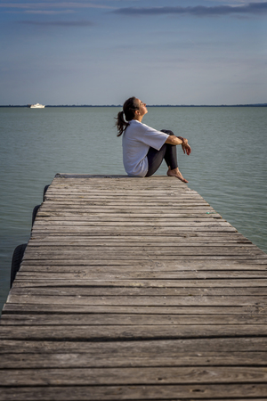 Young girl out on the wooden pier in a lak Balaton of Hungaryの写真素材