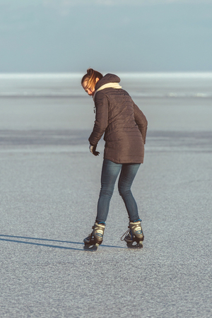 Pretty blonde girl skating on Lake Balaton in Hungary in winterの写真素材