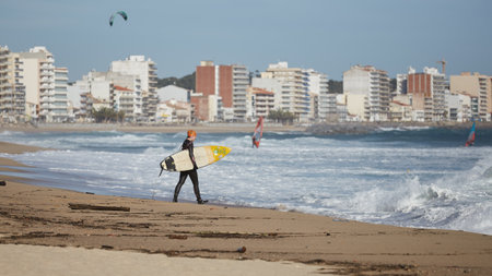 Surfer on the beach in a windy day waiting for big waves in a small Spanish village beach Sant Antoni de Calonge. 01. 02. 2019 Spainのeditorial素材
