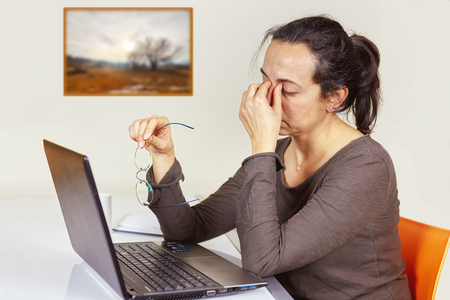 Young spanish women is tired after the work with a computerの写真素材